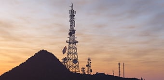 Telecommunications towers on a hilltop at sunset.